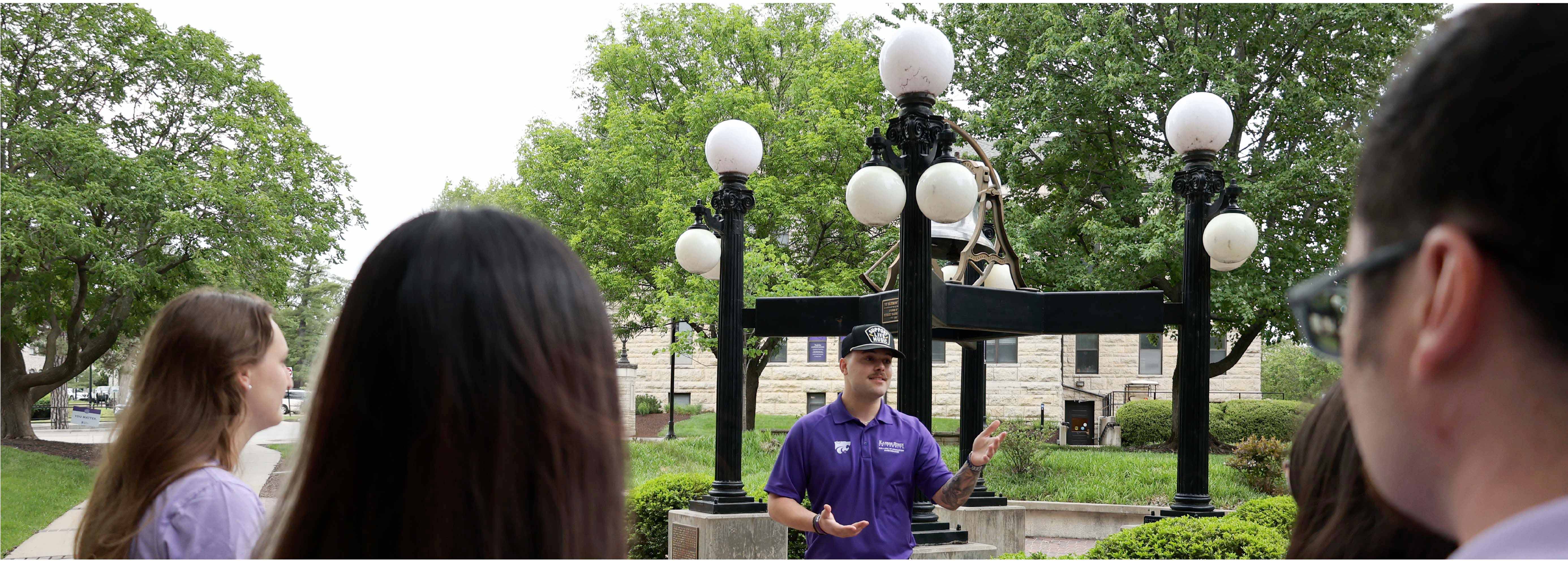 student giving tour in front of the Bluemont Bell in fall